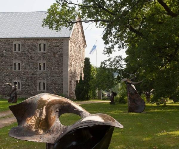 Laila Pullisen veistoksia ja taustalla kivinen kotiseutumuseo.