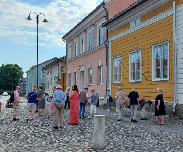 Ihmisiä, värikkäitä puutaloja ja mukulakivikatu vanhankaupungin alueella.