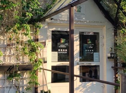 Anttolanhovin valkoinen ulko-ovi, köynnöskasveja ja kesäkukkia