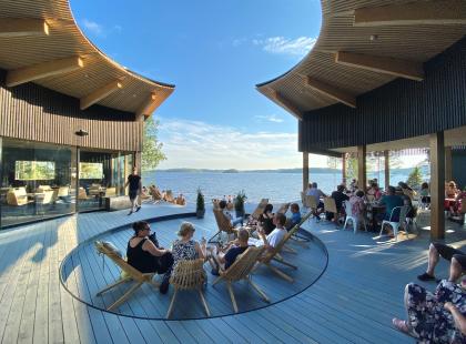 Puinen terassi, ihmisiä tuoleissa, järvimaisema