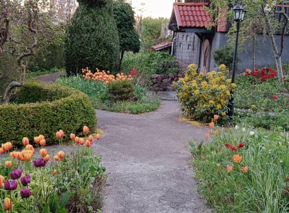 Senses puutarha - polku, kukkia, pensaita, harmaa rakennus