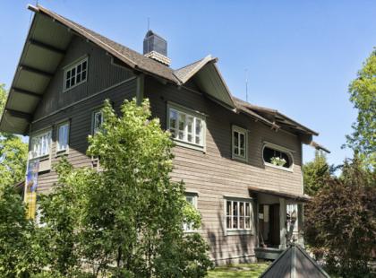 Erkkolan tummansävyinen puurakennus.